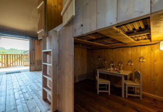 Interior of a safari lodge with wooden furniture, children's play area, and terrace at Vakantiepark IJsselhof.