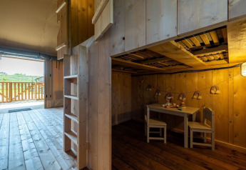 Interno di una tenda safari con arredi in legno, area bambini e terrazza al Vakantiepark IJsselhof.