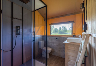 Bagno moderno nella Safarilodge Impala al Vakantiepark IJsselhof, con doccia, WC e vista sulla natura.