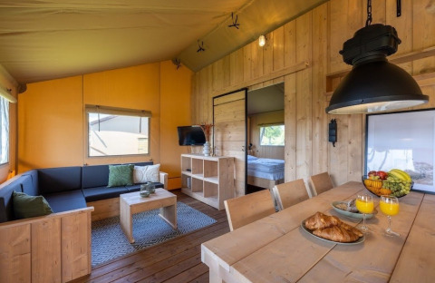 Vue intérieure de la tente Safarilodge Impala au Vakantiepark IJsselhof, avec mobilier en bois et ambiance chaleureuse.