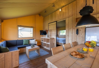Vista interna della tenda Safarilodge Impala al Vakantiepark IJsselhof, arredata in legno e atmosfera accogliente.