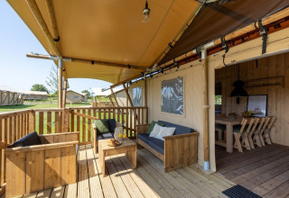 Terraza exterior de la Safarilodge Impala en Vakantiepark IJsselhof, Países Bajos, con muebles de madera.