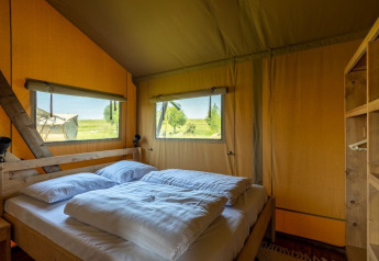 Camera da letto nella tenda Safarilodge Impala al Vakantiepark IJsselhof, Paesi Bassi, con letto matrimoniale.