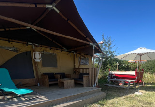 Tienda safari glamping con terraza de madera y sombrilla en Per Amore del Vino, Italia, bajo un cielo azul.