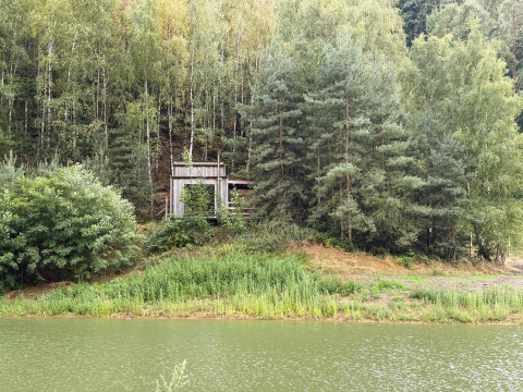 Cabin with hot tub in the Limburg forest, Belgium, Comfort Sweet, viewed from across a pond.