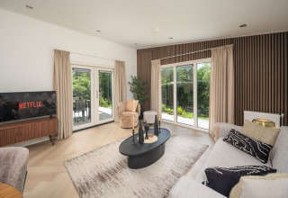 Moderne woonkamer in Loevestein Deluxe met grote ramen, comfortabele meubels en uitzicht op de tuin.