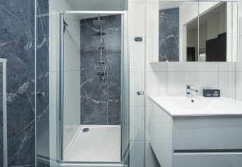 Salle de bains moderne avec douche vitrée, meuble blanc et miroirs au Loevestein Deluxe, Veluwepark de Bosgraaf, Pays-Bas.