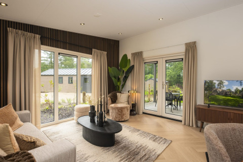 Stijlvolle woonkamer van Loevestein Deluxe met grote ramen, modern interieur en uitzicht op de tuin.
