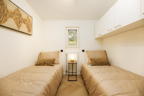 Moderne lodge slaapkamer met twee eenpersoonsbedden bij Loevestein Deluxe, Veluwepark de Bosgraaf, Nederland.