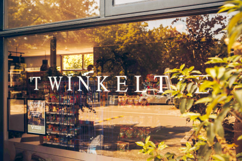 Vitrine du magasin TWINKELT reflétant des arbres, prise à Loevestein Deluxe aux Pays-Bas.