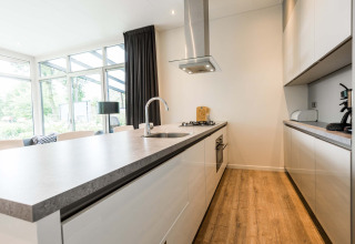 Moderne Küche in der Lodge Module II auf Landgoed de Scheleberg, Niederlande, mit Holzboden und Fenstern.