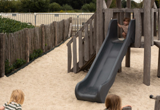 Niños jugando en un parque infantil con tobogán y arena en Feather Down Het Keelven, parque de vacaciones.