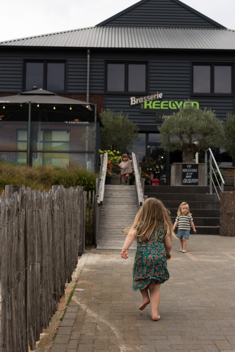 Deux enfants jouent devant la Brasserie Keelven au parc de vacances Feather Down Het Keelven, Brabant-Septentrional.
