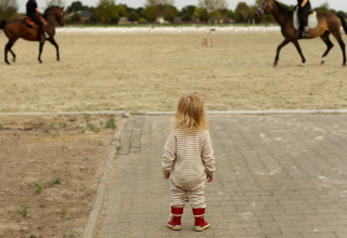 A small child watches two horseback riders; a highlight of Feather Down Het Keelven holiday park in the Netherlands.
