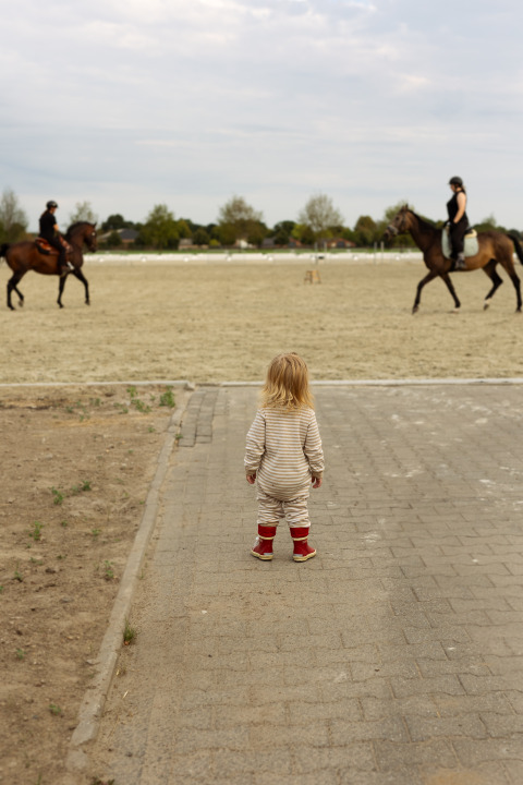 Een peuter kijkt naar twee ruiters te paard, een hoogtepunt van Feather Down Het Keelven in Nederland.