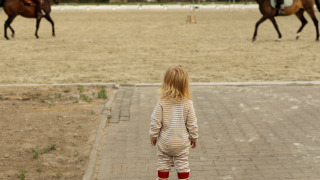 Een peuter kijkt naar twee ruiters te paard, een hoogtepunt van Feather Down Het Keelven in Nederland.