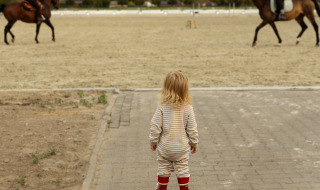 Een peuter kijkt naar twee ruiters te paard, een hoogtepunt van Feather Down Het Keelven in Nederland.