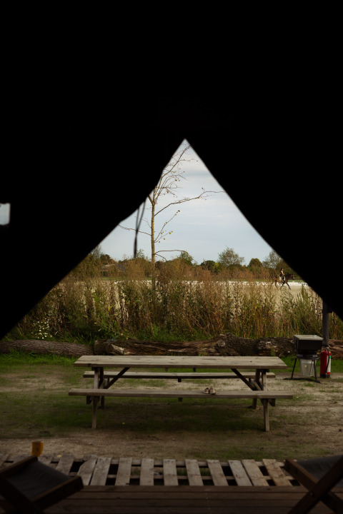 Vista dall'interno di una tenda su tavolo da picnic e natura a Feather Down Het Keelven, Noord-Brabant, Olanda.