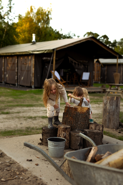 Zwei Kinder spielen mit Holzscheiten im Ferienpark Feather Down Het Keelven in Nordbrabant, Niederlande.