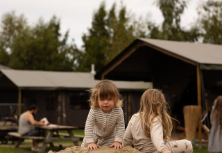 Des enfants jouent sur un tas de sable devant des cabanes au parc de vacances Feather Down Het Keelven, Brabant-Septentrional, Pays-Bas.