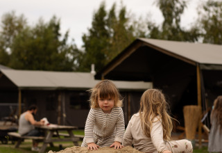 Des enfants jouent sur un tas de sable devant des cabanes au parc de vacances Feather Down Het Keelven, Brabant-Septentrional, Pays-Bas.