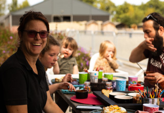 Family enjoying an outdoor meal at a picnic table in Feather Down Het Keelven holiday park, North Brabant.