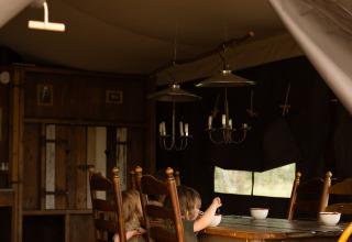 Deux enfants assis à une table en bois dans une tente chaleureuse à Feather Down Het Keelven, Brabant-Septentrional, Pays-Bas.