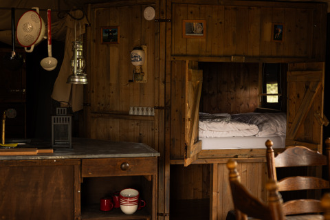 Intérieur de cabane rustique avec lit en alcôve murale et cuisine à Feather Down Het Keelven, Brabant-Septentrional.