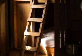 Holzinterieur mit Etagenbett und Leiter im Sonnenlicht, aufgenommen im Feather Down Het Keelven Ferienpark.