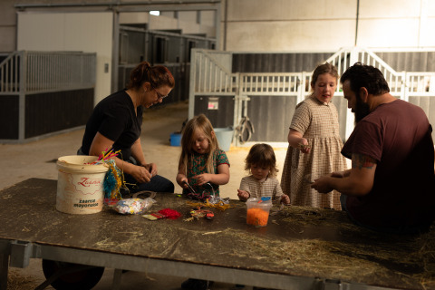 Familia haciendo manualidades en una mesa dentro de un establo en Feather Down Het Keelven, North-Brabant, Países Bajos.