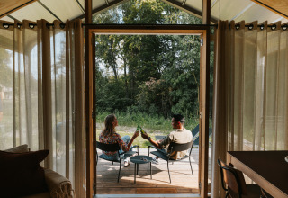 Binnenaanzicht van Wrap house bij Resort de Parel, met twee mensen ontspannend op het buitenterras.