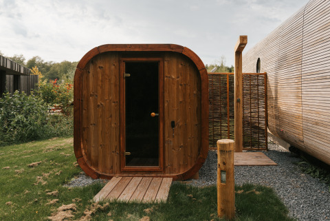 Buitensauna van hout bij Wrap house met badkuip bij Resort de Parel in Nederland, omgeven door natuur.