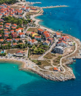 Vista aerea di Povljana, città nella contea di Zadar, Croazia, con case dai tetti rossi e mare blu.