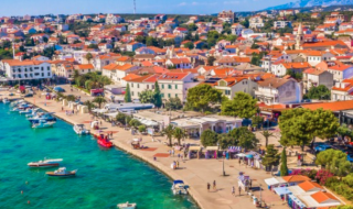 Vista aerea di Povljana, pittoresca città costiera con tetti rossi e mare cristallino in Croazia.