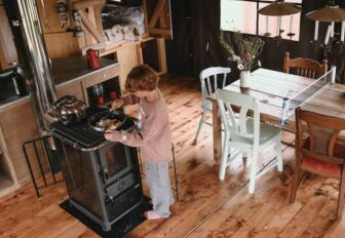 Un bambino cucina su una stufa in una cucina accogliente di tenda safari con tavolo e sedie di legno.