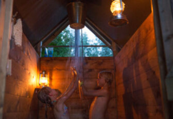 Des enfants profitent d'une douche chaude privée éclairée à la lanterne dans une tente safari en France.
