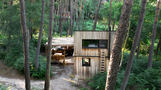 Cabaña revestida de madera con jacuzzi rodeada de altos árboles en el bosque de Limburgo, Bélgica.