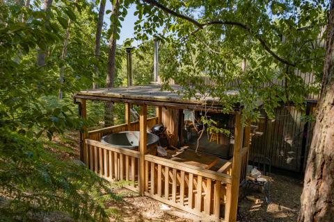 Holzhütte mit überdachter Terrasse und Whirlpool im waldreichen Cosy Cabins in Limburg, Belgien.