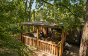 Cabane en bois avec terrasse couverte et jacuzzi nichée dans la forêt chez Cosy Cabins à Limbourg, Belgique.