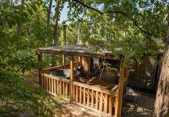 Houten hut met overdekt terras en hot tub in het bos bij Cosy Cabins in Limburg, België.