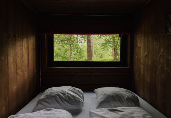 Vue d'une cabane en bois confortable dans la forêt du Limbourg en Belgique, aperçu depuis un lit avec oreillers.
