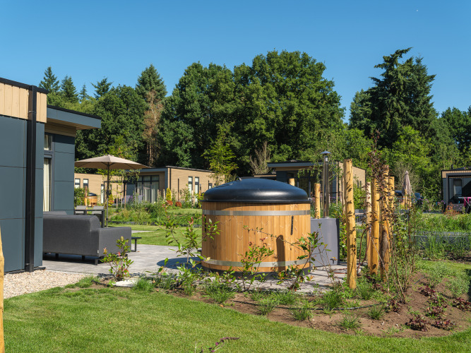 Essenburgh Deluxe Lodge mit Whirlpool im Freien im Veluwepark de Bosgraaf, umgeben von Natur.