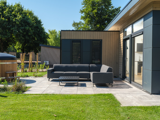 Moderner Terrassenbereich mit Sofa und Tisch bei Essenburgh Deluxe mit Whirlpool im Veluwepark de Bosgraaf.
