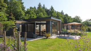 Lodge Essenburgh Comfort moderna con grandi finestre, zona pranzo all’aperto e giardino vicino al bosco.