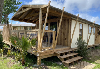 Cabina di legno con veranda al Flower Camping Le Pré des Sables, parco vacanze in Pays de la Loire, Francia.