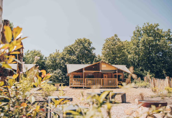 Safari-Zelt Ranger Lodge von vorne, umgeben von Bäumen und Natur an einem sonnigen Tag.