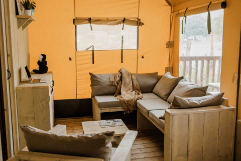 Gezellige safari tent Ranger Lodge in Veluwepark de Bosgraaf met houten zitbanken en warme inrichting.