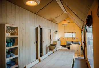 Interno della tenda safari Ranger Lodge al Veluwepark de Bosgraaf, Paesi Bassi, con arredi in legno e zona relax.