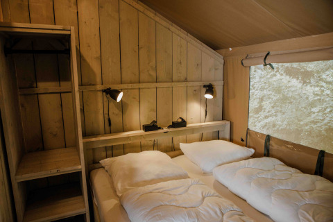 Slaapkamer in Ranger Lodge safaritent Veluwepark de Bosgraaf, Nederland, met warme houten wanden.