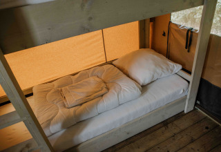 Ein Einzelbett mit weißer Bettwäsche in einem Safarizelt der Ranger Lodge, Veluwepark de Bosgraaf, Niederlande.